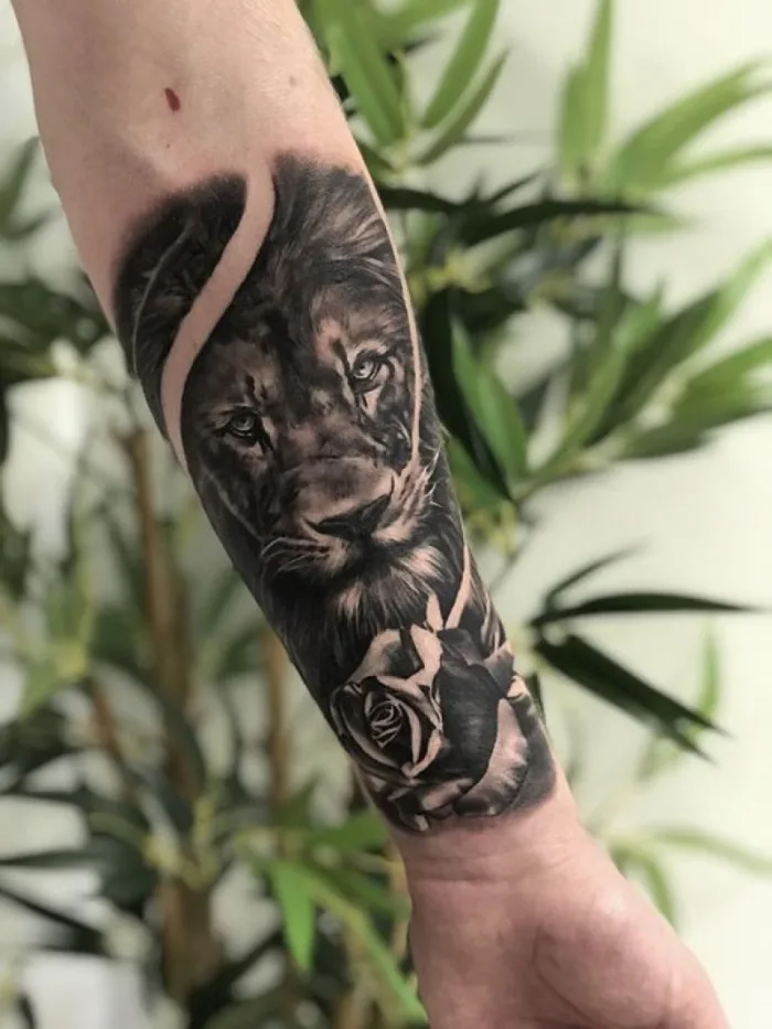 Black and grey realistic lion and rose forearm tattoo by Esther at Unicorn Tattoo Art Collective, Ashford Surrey