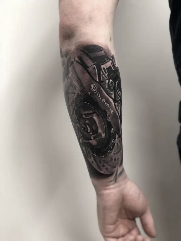 Photorealistic black and grey Brembo brake disc and caliper mechanical forearm sleeve tattoo by Esther, Unicorn Tattoo Art Collective, Ashford Surrey
