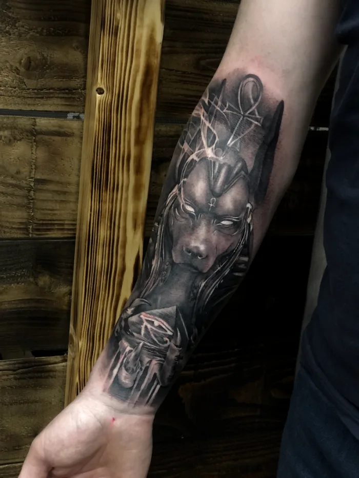 Black and grey Egyptian god Anubis with ankh and Eye of Horus forearm sleeve tattoo by Esther, Unicorn Tattoo Art Collective, Ashford Surrey