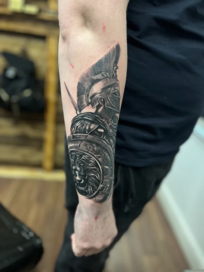 Photorealistic black and grey Roman Spartan warrior with lion shield forearm cover up tattoo by Esther, Unicorn Tattoo Art Collective, Ashford Surrey