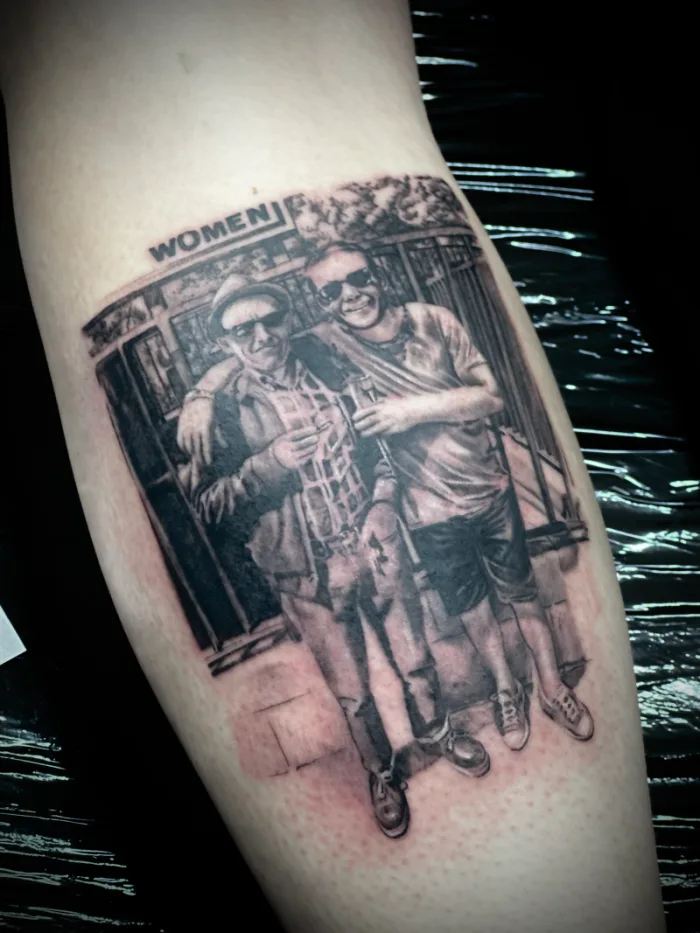 Photorealistic black and grey memorial portrait tattoo of two people on forearm by Esther, Unicorn Tattoo Art Collective, Ashford Surrey