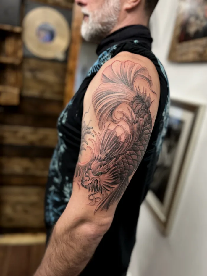 Japanese koi fish half sleeve cover up tattoo in black and grey with green eyes by Esther, Unicorn Tattoo Art Collective, Ashford Surrey