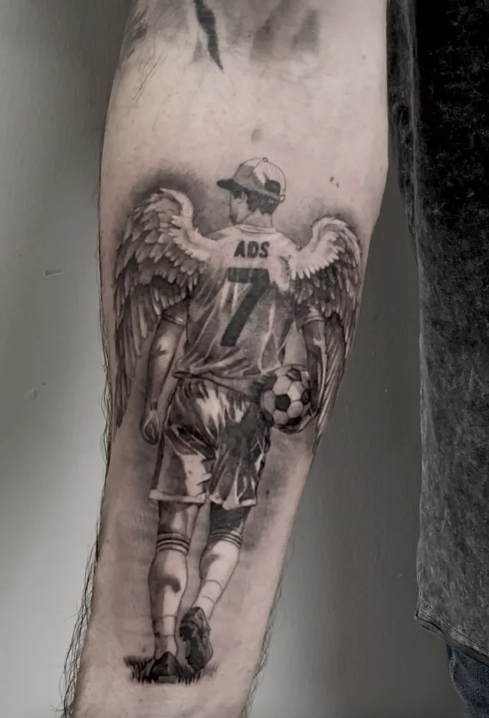 Black and grey memorial angel football player forearm tattoo by Esther, Unicorn Tattoo Art Collective, Ashford Surrey