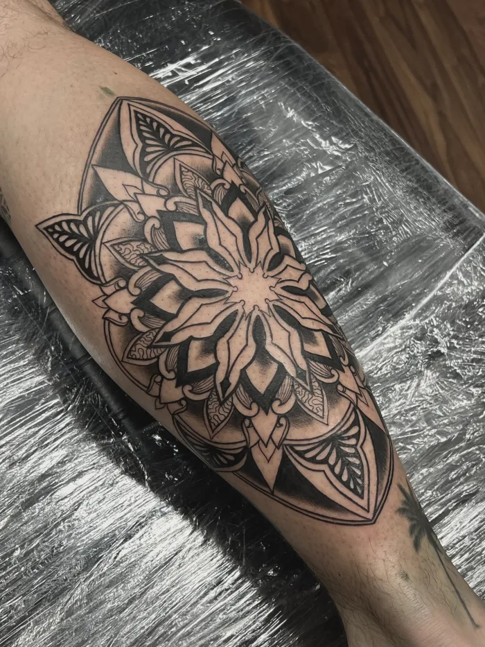 Detailed black and grey mandala calf tattoo created by Esther at Unicorn Tattoo Art Collective in Ashford Surrey, geometric leg tattoo with clean linework and smooth shading.