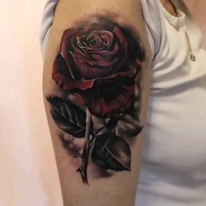 Realistic red and black rose cover up tattoo on upper arm by Esther at Unicorn Tattoo Art Collective, Ashford Surrey