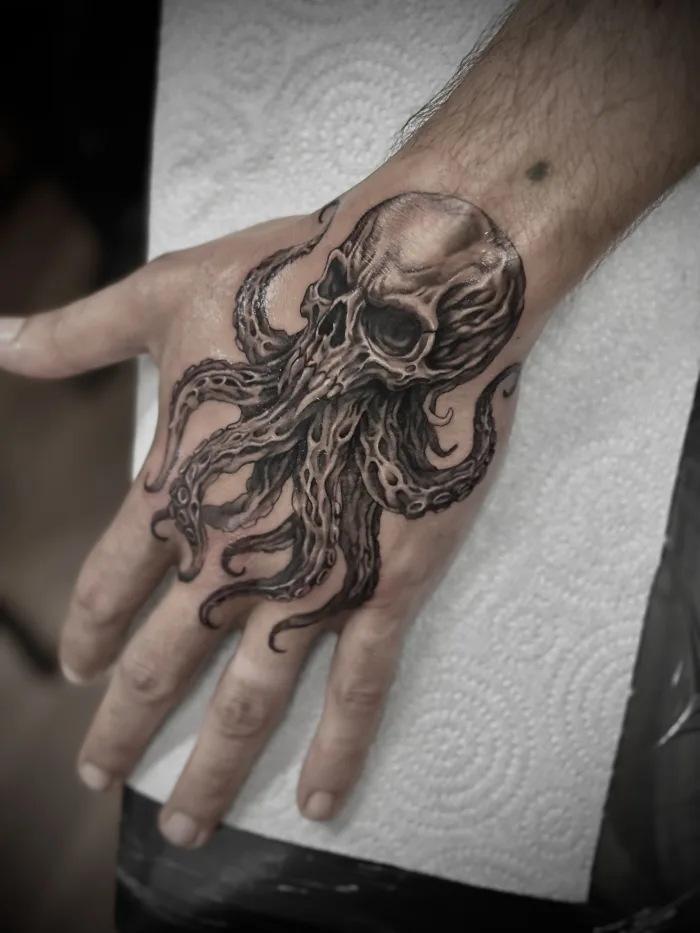 Black and grey octopus hand tattoo with skull design by Esther at Unicorn Tattoo Art Collective in Ashford Surrey
