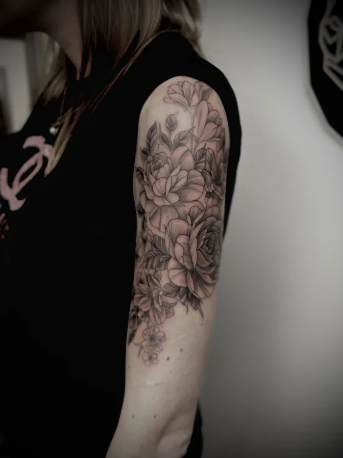 Fine line flower tattoo on upper arm with soft shading, done by Esther at Unicorn Tattoo Art Collective in Ashford, Surrey.