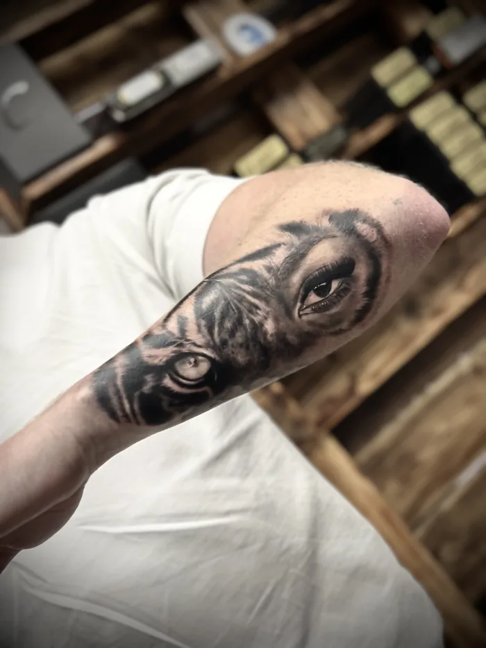 Black and grey forearm tattoo featuring a tiger and realistic eye, done by Esther at Unicorn Tattoo Art Collective in Ashford, Surrey.
