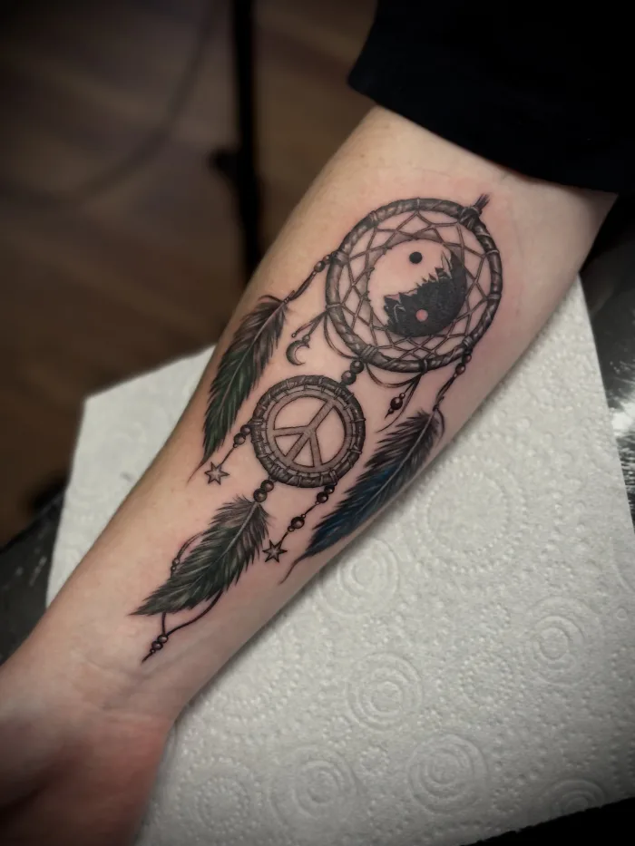 Dreamcatcher forearm tattoo with yin yang and peace symbol by Esther at Unicorn Tattoo Art Collective Ashford Surrey