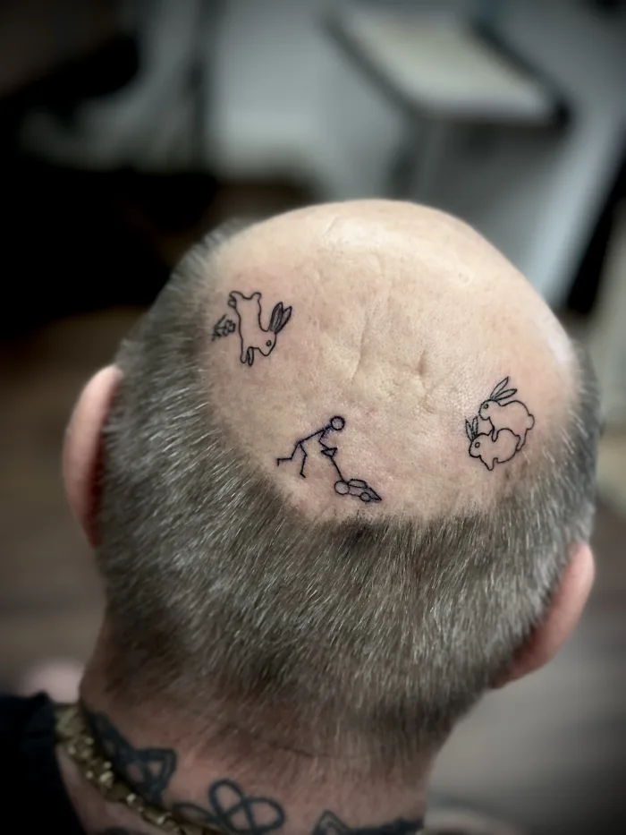 Minimalist fine line tattoo by Esther at Unicorn Tattoo Art Collective in Ashford, Surrey, featuring small playful linework designs on the head