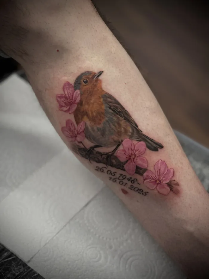 Memorial robin tattoo with pink flowers and dates by Esther at Unicorn Tattoo Art Collective in Ashford, Surrey