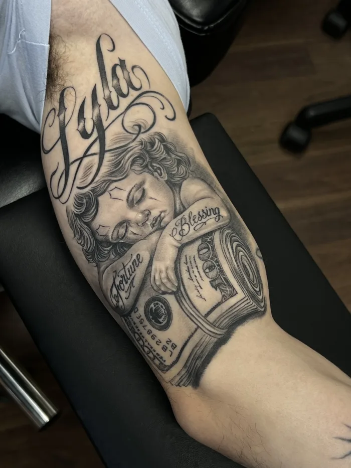 Healed black and grey cherub and lettering tattoo at Unicorn Tattoo Art Collective in Ashford, Surrey