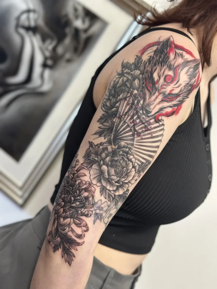 Japanese style cover-up sleeve in progress by Esther featuring a fox mask, fan and flowers in black and grey with red details