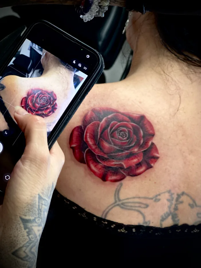Red rose cover-up tattoo on the upper back by Esther at Unicorn Tattoo Art Collective in Ashford, Surrey
