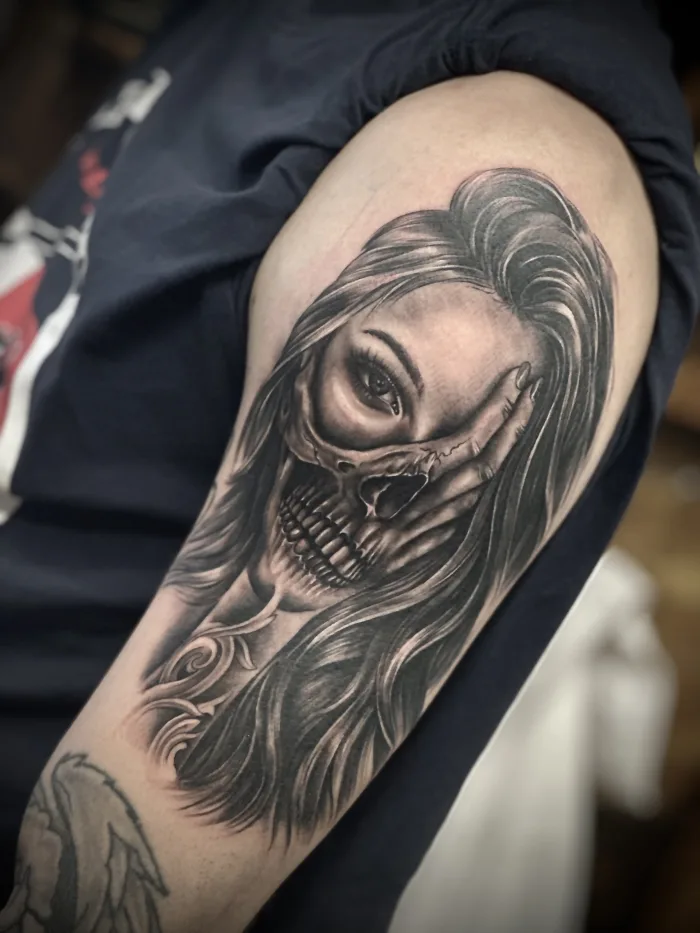 Black and grey skull woman portrait tattoo on the upper arm by Esther in Ashford, Surrey