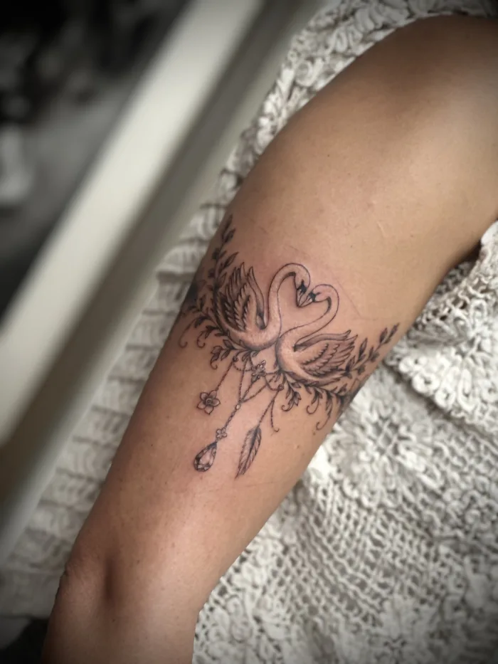 Fine line swan tattoo by Esther at Unicorn Tattoo Art Collective in Ashford, Surrey, featuring delicate botanical and ornamental details.